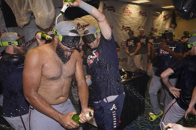 Atlanta Braves relief pitcher Kenley Jansen, left, is doused with champagne as players celebrate in the club house after they clinched their fifth consecutive NL East title by defeating the Miami Marlins 2-1, in a baseball game, Tuesday, Oct. 4, 2022, in Miami. (AP Photo/Wilfredo Lee)