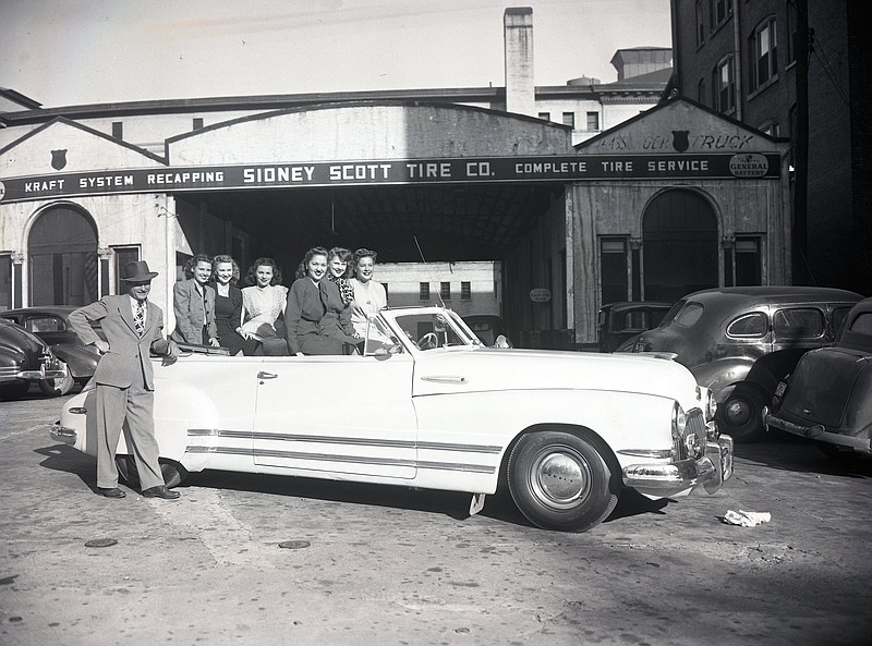 Chattanooga News-Free Press archive photo by Delmont Wilson via ChattanoogaHistory.com / This newspaper photo was published on April 30, 1947, to illustrate an article about a new auto paint system offered by Sidney Scott Tire Company on Georgia Avenue. Pictured are: W.F. Dixon, company sales manager (standing) and seated from left rear, Ann Jones, Norma Roberts and Evelyn Worthington. Seated from front left are Ann Howard, Dot Morgan and Lillian Hatchett.