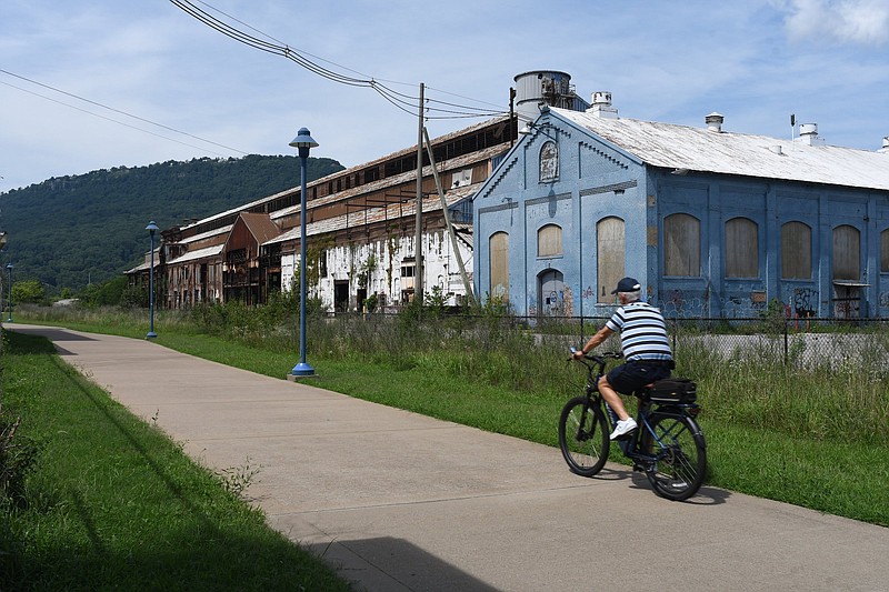 Staff Photo by Robin Rudd / A bicyclist uses the Tennessee Riverwalk as he passes the former Wheland Foundry on Oct. 14, 2022. The former U.S. Pipe/Wheland Foundry property is the site of a proposed large-scale redevelopment in the South Broad District, with a new stadium for the Chattanooga Lookouts as a centerpiece.