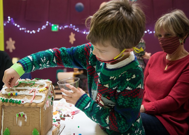 Staff file photo / Six-year-old Dylan Martin adds coconut shavings to his gingerbread house as his grandmother Pat watches behind him during a gingerbread workshop at the Creative Discovery Museum on Nov. 29, 2020. This year's workshops at the children's museum start Nov. 25.
