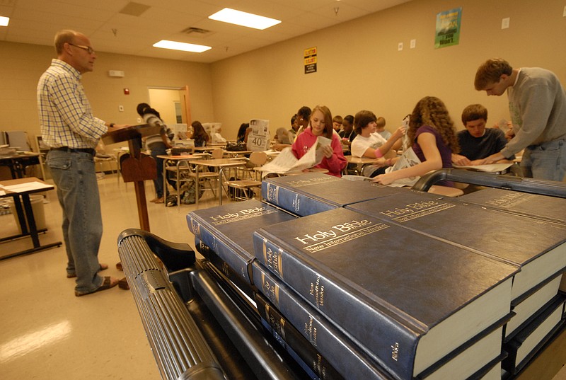 Staff Photo /  A book cart with Bibles sits to the side as Jeff Fairbanks, Bible history teacher at East Hamilton Middle/High School and Tyner Academy, teaches one of his classes at East Hamilton in 2010. More than 1,000 people are meeting to raise money to fund the program.