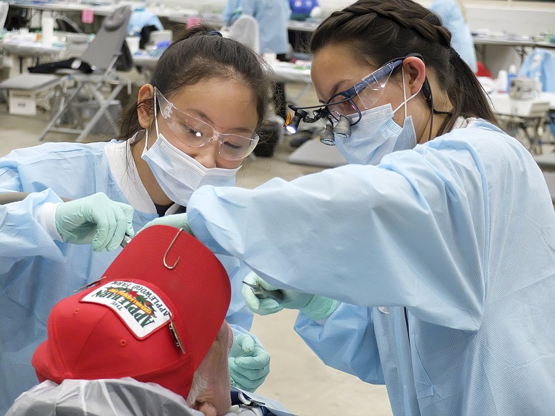 Staff photo by Tim Barber/ Annice Chew, left, a senior at the University of Tennessee Knoxville, and Kim Taylor Freeman, third year student at the University of Tennessee Health Sciences Center in Memphis, perform dental work Saturday at the RAM Clinic inside Camp Jordan Arena.