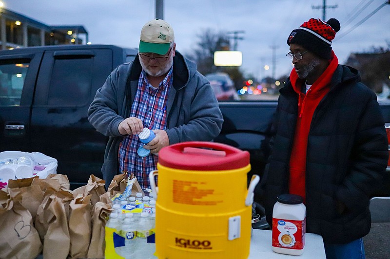 Staff photo by Olivia Ross  / Jon Rector and members with The Union Gospel Mission hand out coffee and sack lunches outside the Budgetel on Wednesday. After being told to leave the building by early Wednesday morning, many residents of the Budgetel in East Ridge begin packing their belongings. The building is said to be shut down due to high crime.