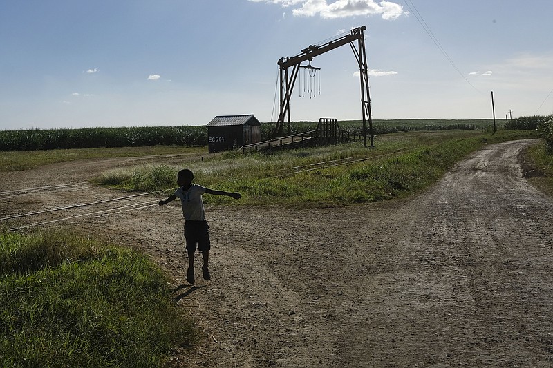 FILE - A youth plays near the machine where the sugar cane is weighed in the Lima batey, or neighborhood, in La Romana, where Central Romana Corporation, Ltd. operates its sugar operations in Dominican Republic, Nov. 17, 2021. The U.S. government announced Nov. 23, 2022 that it will detain all imports of sugar and related products made in the Dominican Republic by Central Romana Corporation, Ltd. amid allegations that it uses forced labor. (AP Photo/Matias Delacroix, File)