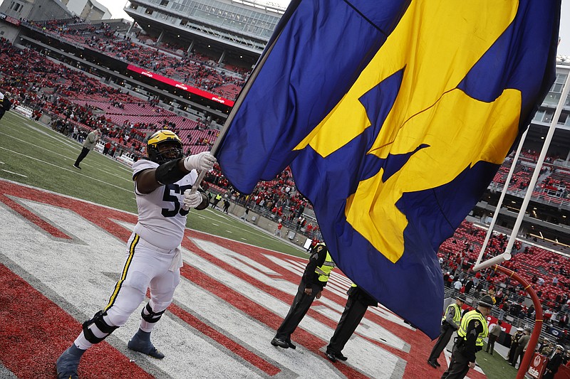 AP photo by Jay LaPrete / Michigan offensive lineman Trente Jones waves the school flag to celebrate the Wolverines' rivalry win at Ohio State on Saturday.