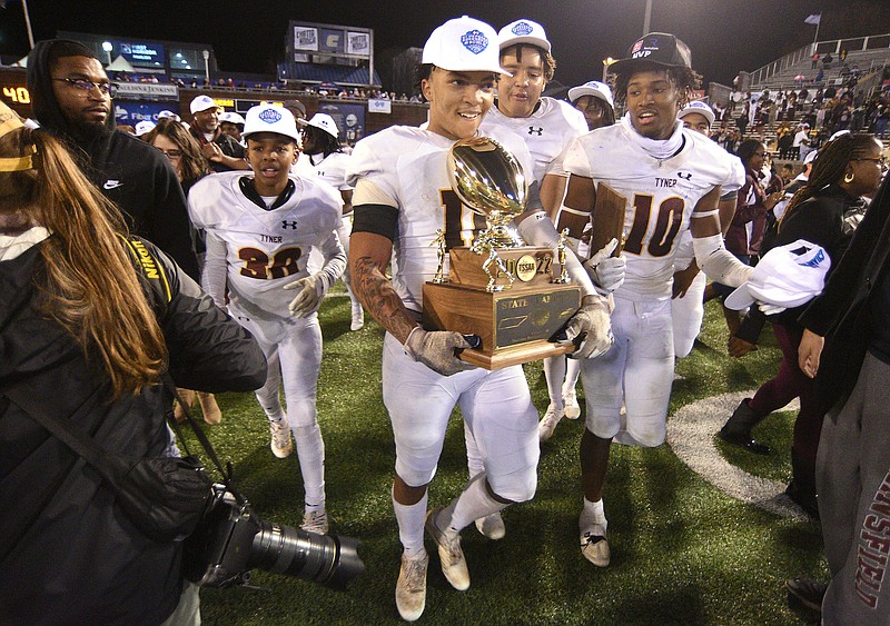Staff photo by Matt Hamilton / Tyner's Travis Ruffin carries the state championship trophy across the field with teammates after the Rams won the TSSAA Class 2A BlueCross Bowl on Saturday at Finley Stadium.