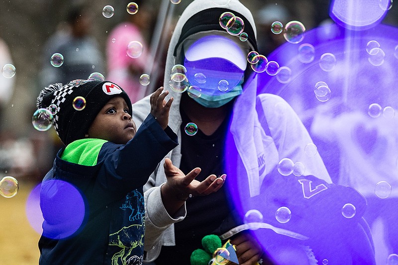 Staff file photo / Cannon Montgomery,1, reaches out for bubbles as his mother Briana Deloach stands behind him during the Winter Break Spectacular on Dec. 17, 2021.