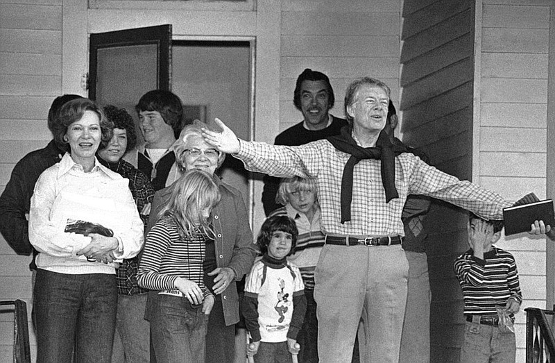 President Jimmy Carter wishes everybody a Merry Christmas as he leaves the home of his mother-in-law in Plains, Georgia on Dec. 25, 1978. From left: Rosalynn Carter, Amy Carter, Mrs. Allie Smith, his mother-in-law, wearing glasses, and president. Others in the background are unidentified family members and friends. (AP Photo/Charles Tasnadi)