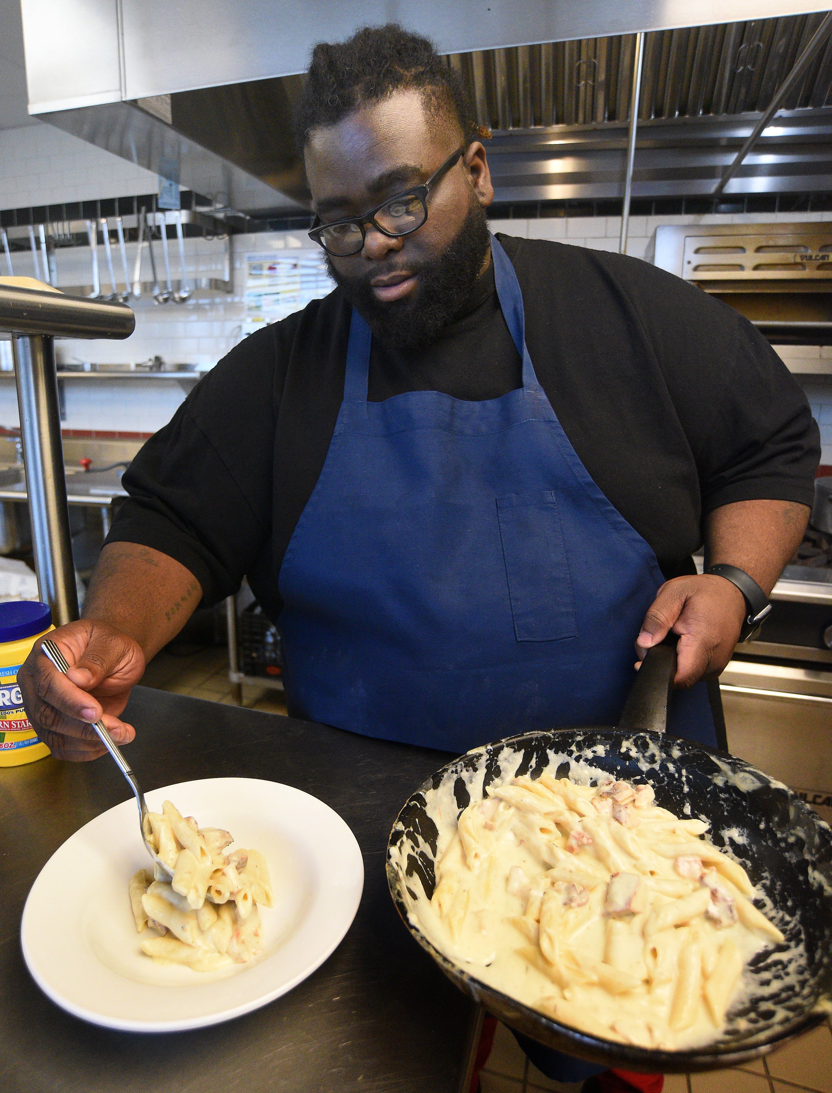 Staff Photo by Matt Hamilton / Chef Cornelius Lathan serves a plate of baked smoked chicken Alfredo at the Kitchen Incubator of Chattanooga.