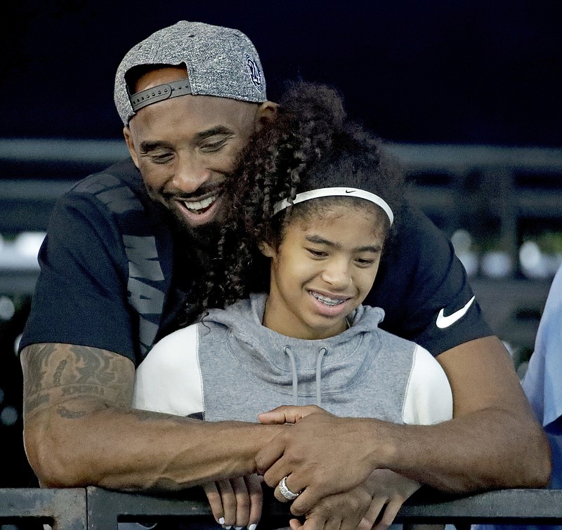 AP Photo/Chris Carlson, File /  In this July 26, 2018, file photo, former Los Angeles Laker Kobe Bryant and his daughter Gianna watch during the U.S. national championships swimming meet in Irvine, Calif. They died in a helicopter crash in January 2020.