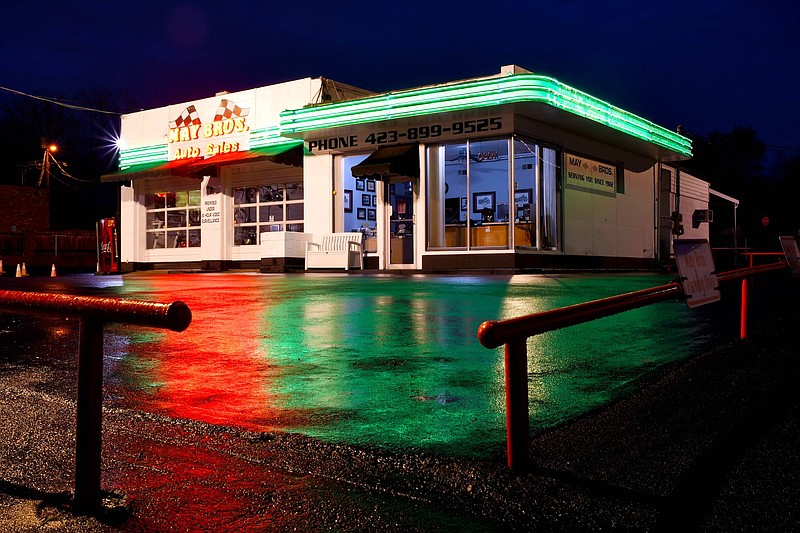 Staff Photo by Robin Rudd / The overnight rain has left the parking lot of May Brothers Auto Sales a watercolor smear of neon color.  The East Brainerd Road business, founded in 1982, is housed in two-bay Art Deco gas station.  The photograph was made on March 2, 2023.