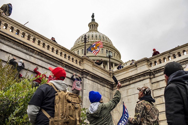 File photo/Jason Andrew/The New York Times / Protesters climb the walls of the Capitol in Washington on Jan. 6, 2021.