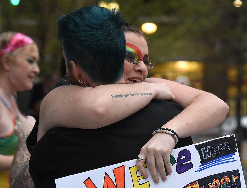 Staff photo by Matt Hamilton / Chase Peace Demoanz holds a sign and hugs Cameron Rigler during a pride rally at Miller Park on March 1.