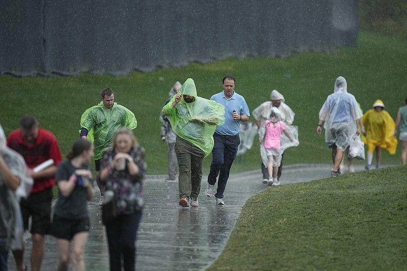 AP photo by Eric Gay / Spectators leave TPC Sawgrass in the rain Friday afternoon with the second round of The Players Championship suspended because of the weather.
