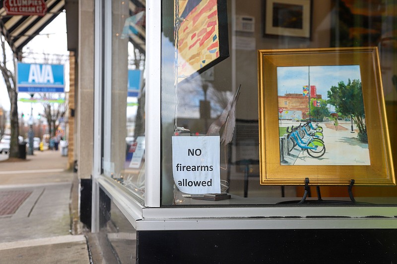 Staff Photo By Olivia Ross / A "No Firearms Allowed" sign is posted in the window of the In-Town Gallery on Frazier Avenue.