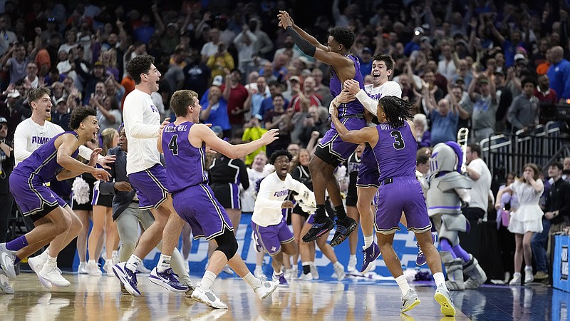 AP photo by Chris O'Meara / Furman guard JP Pegues, third from right, celebrates with his teammates after the 13th-seeded Paladins beat South Region No. 4 seed Virginia in the first round of the NCAA tournament Thursday in Orlando, Fla.