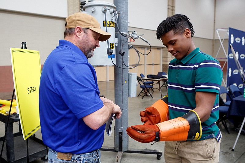 Staff File Photo / EPB Operations Superintendent Steve Raulston, left, shows a Hunter Middle School eighth- grader lineman gear during a Get (Future) Ready school choice fair at the Chattanooga Convention Center on Wednesday, Jan. 15, 2020.