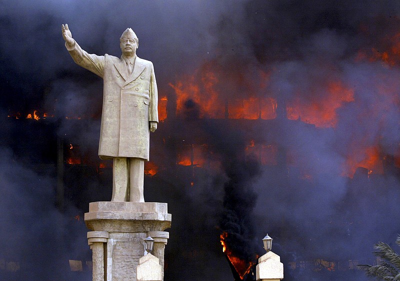 File photo/Tyler Hicks/The New York Times / A statue of Saddam Hussein stands in front of the burning National Olympic Committee building in Baghdad, on April 19, 2003. The invasion of Iraq succeeded in toppling Saddam Hussein.