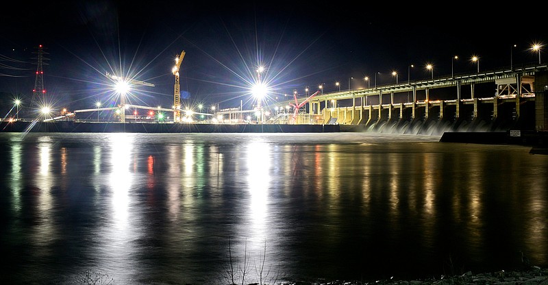 Staff File Photo By Robin Rudd / Lit by construction lights from the ongoing building of a new lock at Chickamauga Dam, water courses through the spillways in January 2022.