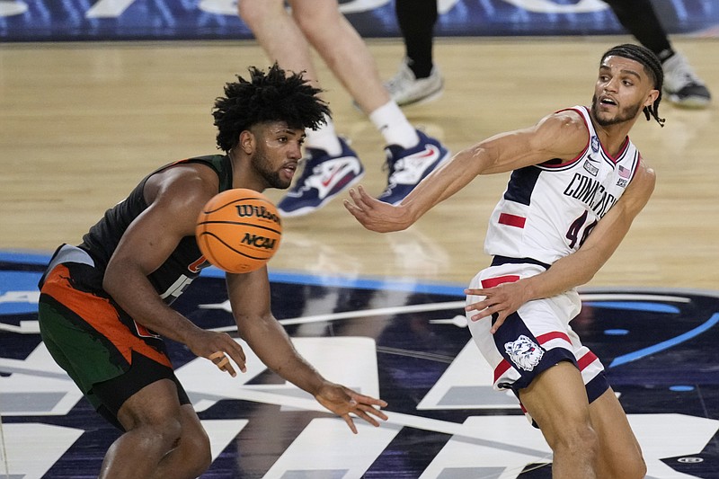 AP photo by Godofredo A. Vasquez / UConn guard Andre Jackson Jr., right, passes around Miami forward Norchad Omier during an NCAA tournament Final Four game Saturday night in Houston.