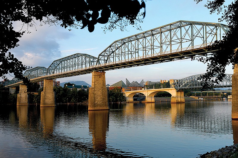 Staff Photo by Robin Rudd / Chattanooga icons line up under the rising sun in this Tennessee River view from Coolidge Park. The Walnut Street Bridge, the Market Street Bridge, Lookout Mountain, and the Tennessee Aquarium are some of Chattanooga's best-known attractions.