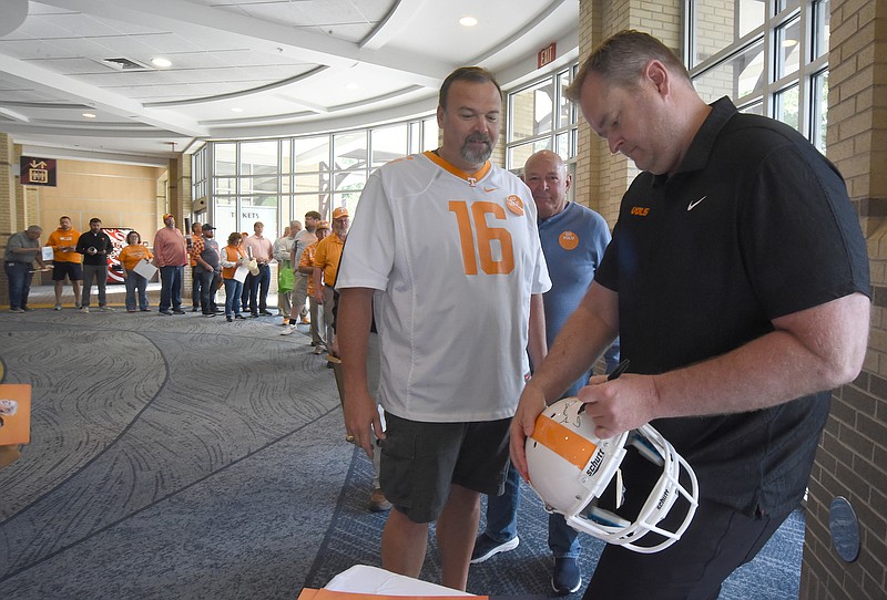 Staff photo by Matt Hamilton / University of Tennessee football coach Josh Heupel autographs a football helmet for Chattanooga resident Anthony Lytle during the Big Orange Caravan event at the Chattanooga Convention Center on Monday, May 1, 2023.