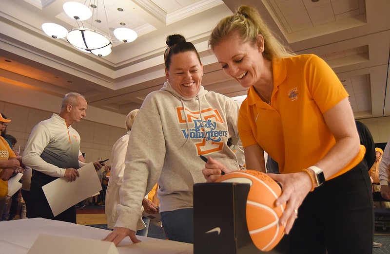 Staff photo by Matt Hamilton / University of Tennessee women's basketball coach Kellie Harper, right, autographs a basketball for Knoxville resident Trixie Moses during the Big Orange Caravan event at the Chattanooga Convention Center on Monday.