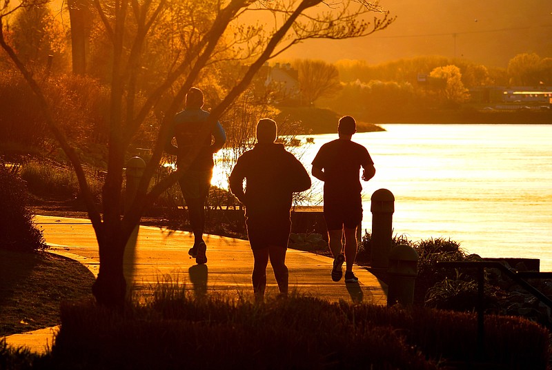 Staff Photo by Robin Rudd / Three men run into the sunrise on the Tennessee Riverwalk in Coolidge Park.