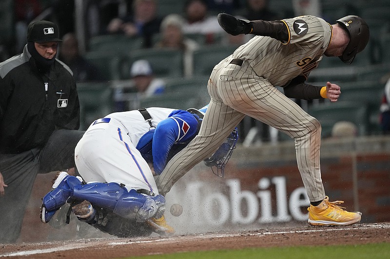 San Diego Padres' Jake Cronenworth, right, scores on a Rougned Odor ground ball as the ball get away from Atlanta Braves catcher Travis d'Arnaud during the fourth inning of a baseball game Saturday, April 8, 2023, in Atlanta. (AP Photo/John Bazemore)