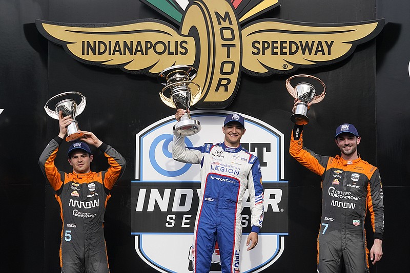 AP photo by Darron Cummings / Alex Palou, center, holds the first-place trophy after winning Saturday's GMR Grand Prix on the road course at Indianapolis Motor Speedway. Pato O'Ward, left, finished second and Alexander Rossi, right, was third.