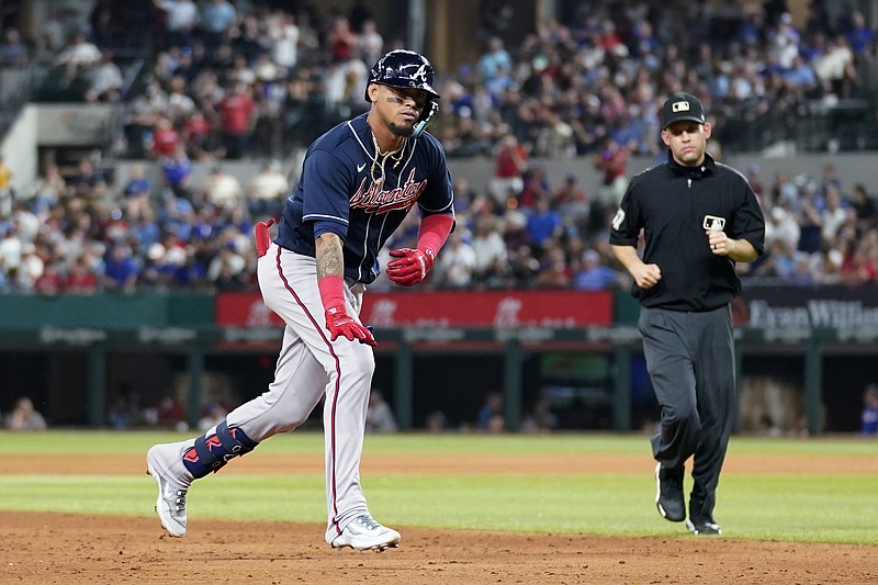 AP photo by Tony Gutierrez / Field umpire Dan Merzel watches as Orlando Arcia celebrates while rounding third base Wednesday night in Arlington, Texas. Arcia hit a go-ahead solo home run for the Atlanta Braves in the top of the ninth inning against the Texas Rangers.