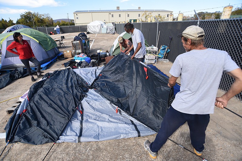 Staff photo by Matt Hamilton / Ann-Marie Fitzsimmons, left, talks to Eric Durrett, right, and others as they assemble a tent at the homeless camp at the intersection of 12th Street and Peeples streets on Oc. 28.