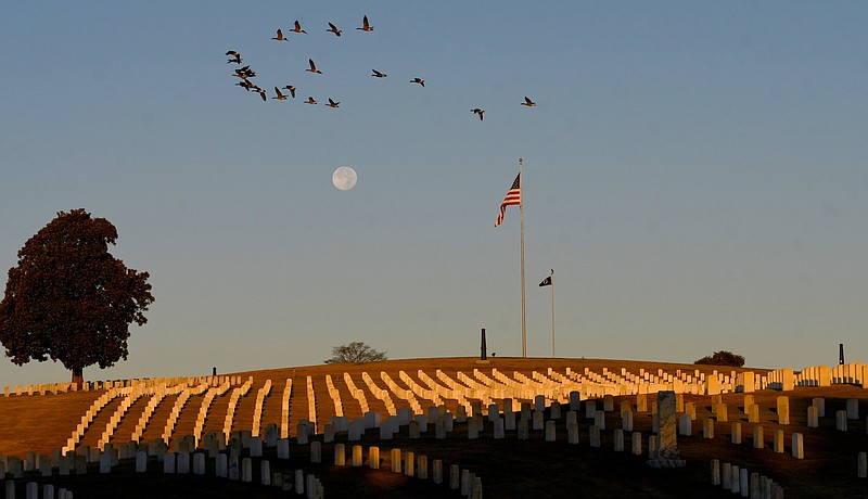 Staff File Photo By Robin Rudd / Canada geese fly past a crest of the Chattanooga National Cemetery, as the rising sun illuminates headstones on November 9, 2022.