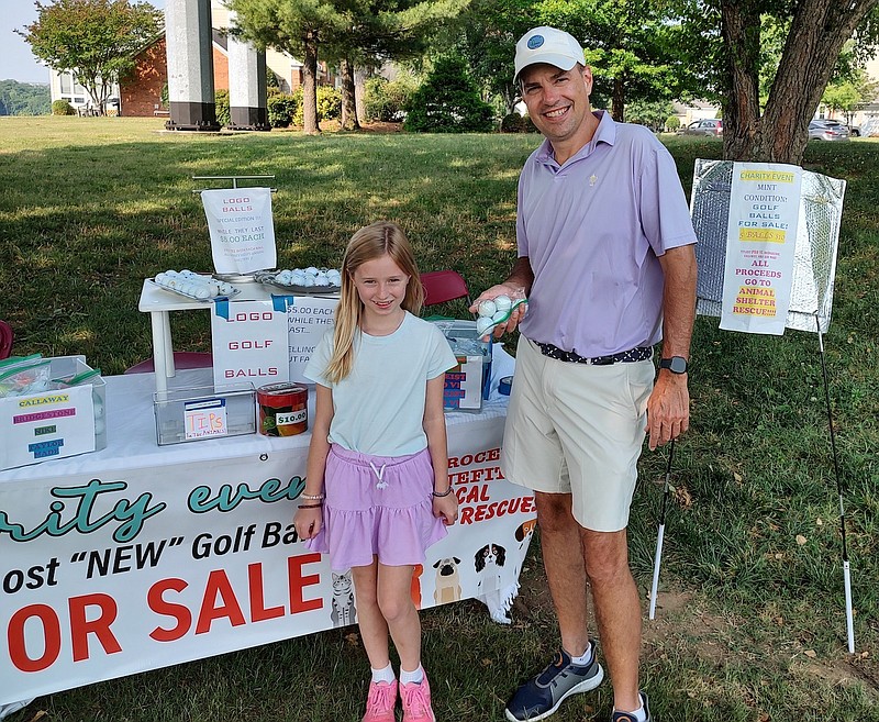 Staff Photo by Mike Pare / Elise Marx stands in front of her animal rescue golf ball sales kiosk Friday. At right is Brian Kopet, who was golfing at Chattanooga Golf and Country Club when he stopped by and made a purchase.