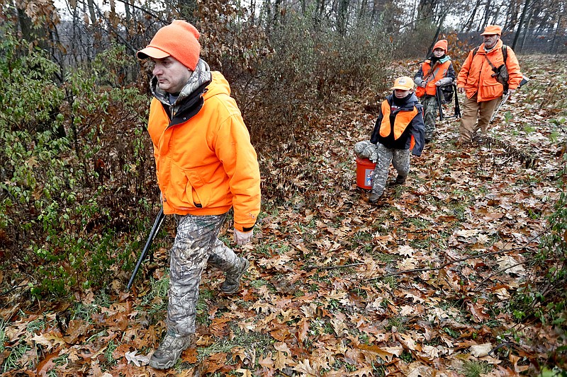 AP photo by Keith Srakocic / Dominick Cerminaro, left, walks ahead of his sons Paul, center left, and Santo, center right, and his father Santo as they enter the woods to go deer hunting in November 2018 in Zelienople, Pa.