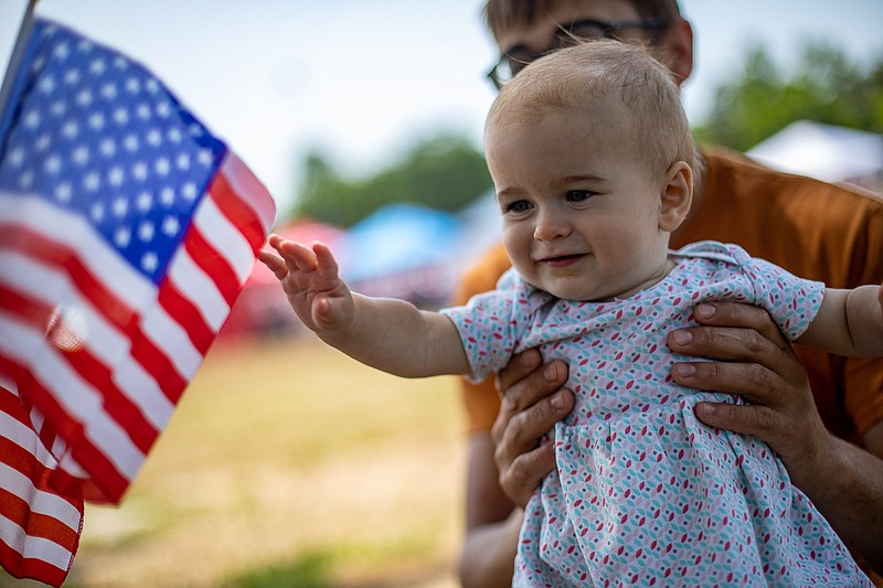 Staff file photo / Lauren Lawson, not pictured, holds two American flags up to her granddaughter Magnolia Moore's face as her father Benjamin holds her during a Fourth of July celebration in Soddy-Daisy on July 3, 2021.