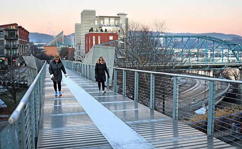 Staff Photo by Robin Rudd / Two walkers cross the Holmberg Bridge linking the Riverfront with the Bluff View Arts District before sunrise in this 2022 view of Chattanooga, named the second worst-run city in America.