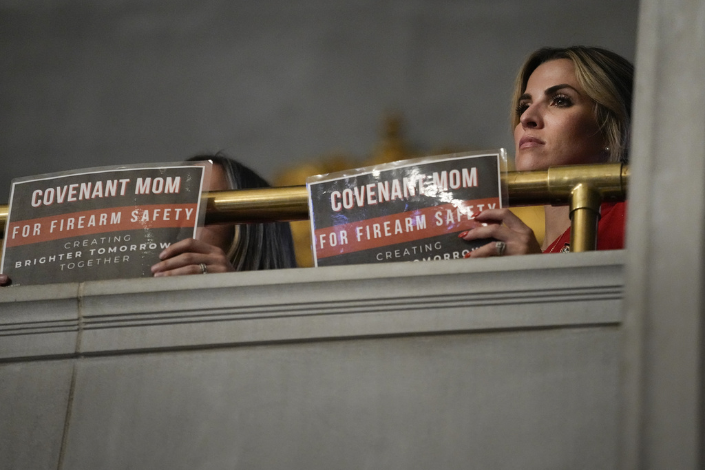 Covenant School parent Mary Joyce holds a sign in the House chamber gallery asking for firearm safety laws during a special session of the state legislature Monday, Aug. 21, 2023, in Nashville, Tenn. (AP Photo/George Walker IV)