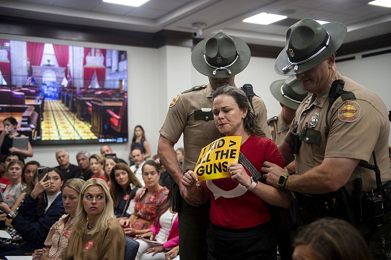 On Tuesday, Allison Polidor is escorted out of the room by Tennessee state troopers for holding a sign reading, "1 Kid > All The Guns," during a special session of the state legislature on public safety in Nashville. (Nicole Hester/The Tennessean via AP)