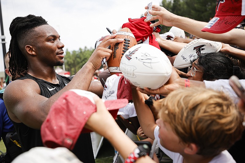 AP photo by Alex Slitz / Atlanta Falcons rookie running back Bijan Robinson signs autographs for fans at training camp on July 29 in Flowery Branch, Ga. Robinson, a first-round draft pick, is expected to be a big part of the offense with his ability to not only run the ball but contribute as a target in the passing game.