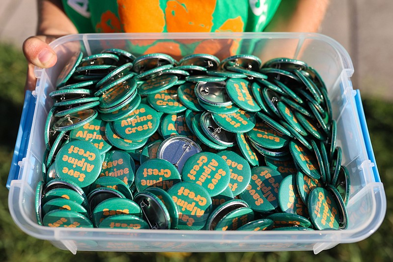 Staff photo by Olivia Ross / “Save Alpine Crest” buttons are handed out at a community meeting on Aug. 30 at Red Bank Community Center, where many stakeholders spoke out in favor of saving the school.