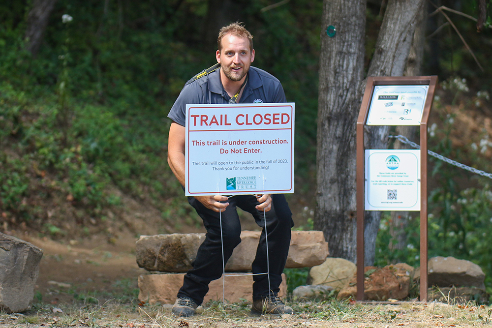 Staff photo by Olivia Ross / Quentin Miller, GIS Manager and Field Operations Specialist with Tennessee River Gorge Trust, happily removes the “trail closed” sign.