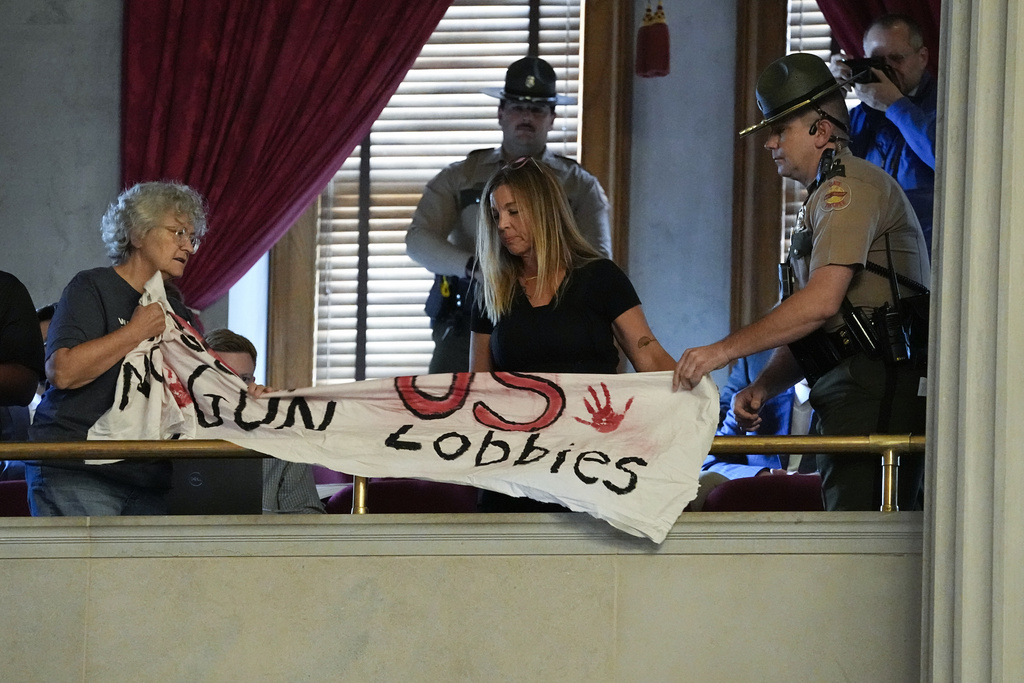 A Tennessee State Trooper, right, removes a demonstrator's banner advocating for gun law reform from the House chamber during a special session of the state legislature on public safety Aug. 28 in Nashville. (AP Photo/George Walker IV)