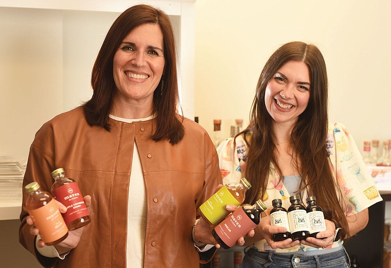 Photography by Matt Hamilton / Maven Table owners Rachel Wanamaker, left, and Kaleena Goldsworthy-Warnock hold a selection of their drink products.
