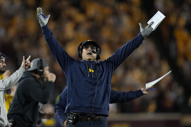 AP photo by Abbie Parr / Michigan coach Jim Harbaugh signals for a touchdown while looking at the replay board during an Oct. 7 game at Minnesota.