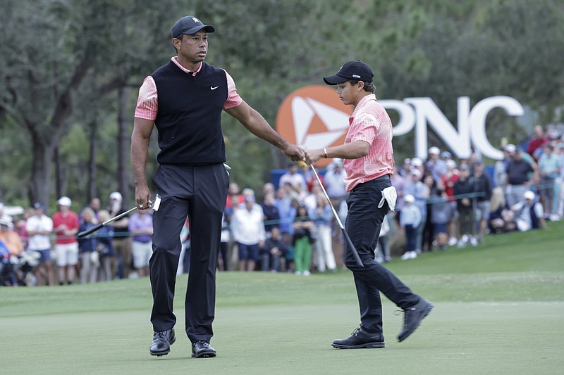 AP photo by Kevin Kolczynski / Tiger Woods congratulates his son Charlie after they finished the first round of the PNC Championship on Dec. 17, 2022, in Orlando, Fla.