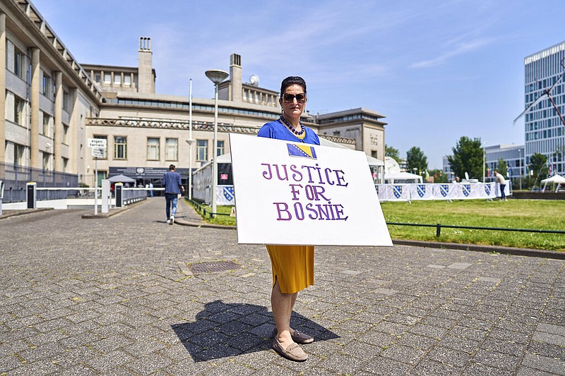 Fatma Aktas of the Mothers of Srebrenica activist group, holds a poster outside the International Residual Mechanism for Criminal Tribunals in The Hague, Netherlands, Tuesday, June 8, 2021. The United Nations court delivers its verdict in the appeal by former Bosnian Serb military chief Ratko Mladic against his convictions for genocide and other crimes and his life sentence for masterminding atrocities throughout the Bosnian war. (AP Photo/Phil Nijhuis)