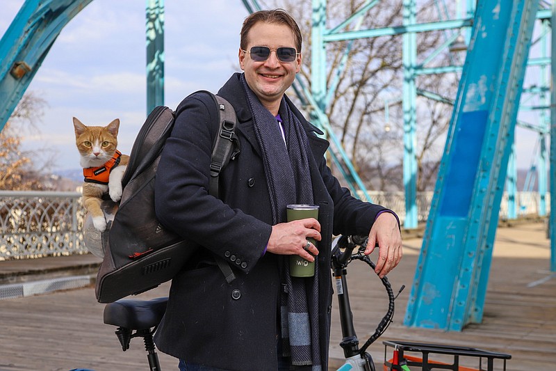 Staff photo by Olivia Ross / Cameron Merriman poses for a photo with his cat, Nugget, in front of the Walnut Street Bridge on Saturday.