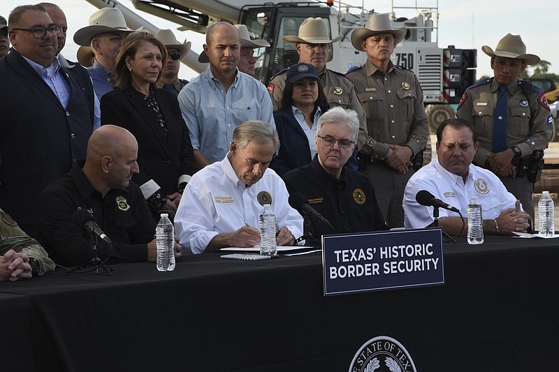 Photo/Valerie Gonzalez/The Associated Press / Gov. Greg Abbott signs three bills into law at a border wall construction site in Brownsville, Texas on Monday, Dec. 18, 2023, that will broaden his border security plans and add funding for more infrastructure to deter illegal immigration.