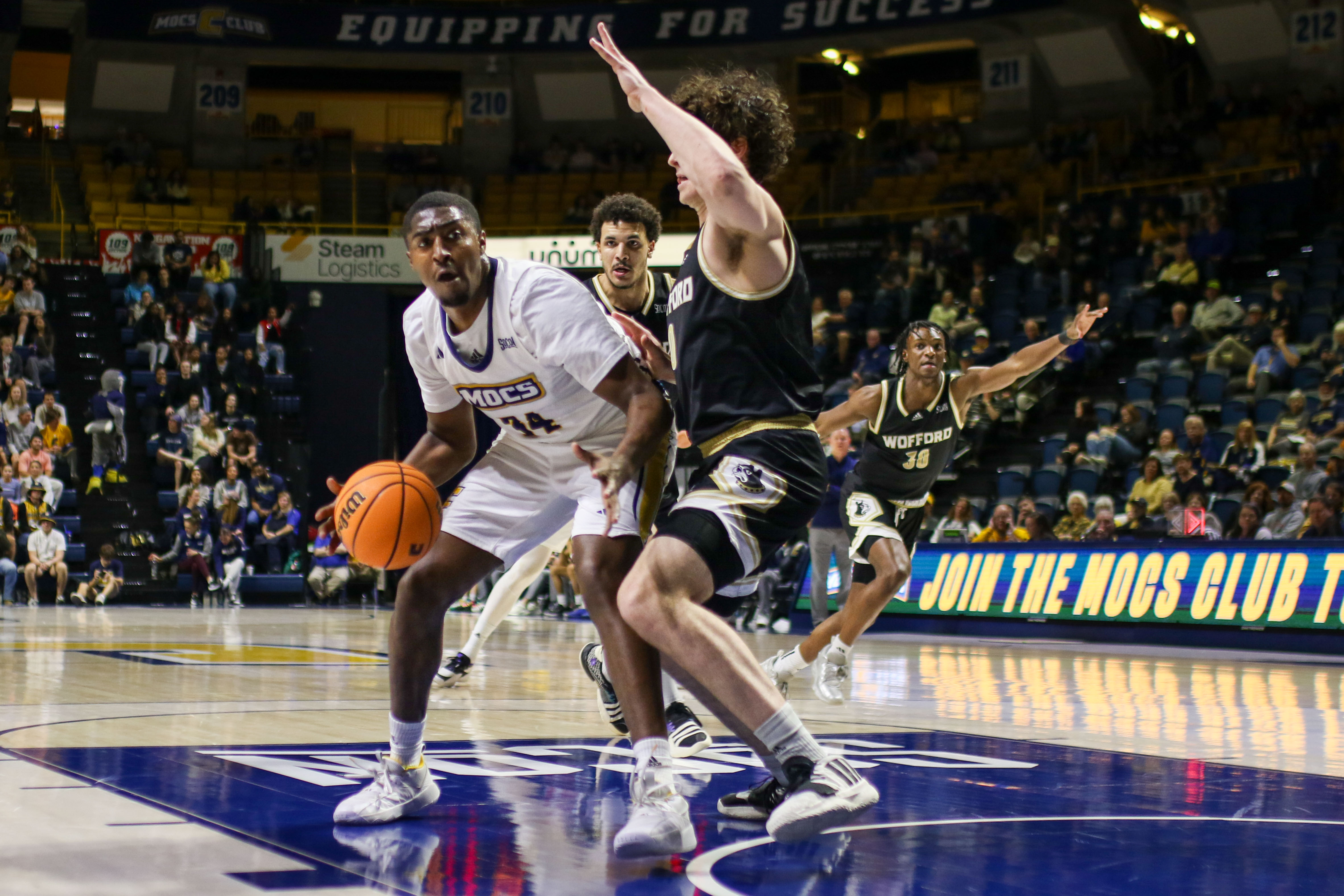 Staff photo by Olivia Ross / UTC's Randy Brady (34) dribbles around Wofford's Jackson Sivills (0). UT Chattanooga took on Wofford at home on Wednesday, February 21, 2024.